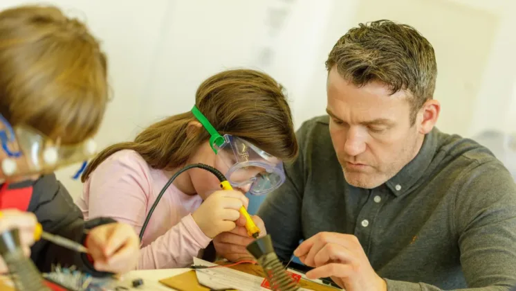 Man supervises girl using scientific tools