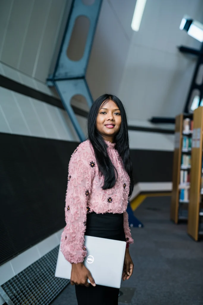 Female international student standing in the ATU Galway City Library with laptop in her hand