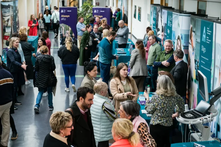 Crowd of people speaking to staff at stands during the Postgraduate Information Day in Sligo