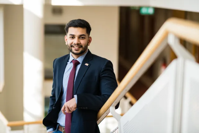 Male international student standing on staircase in a suit