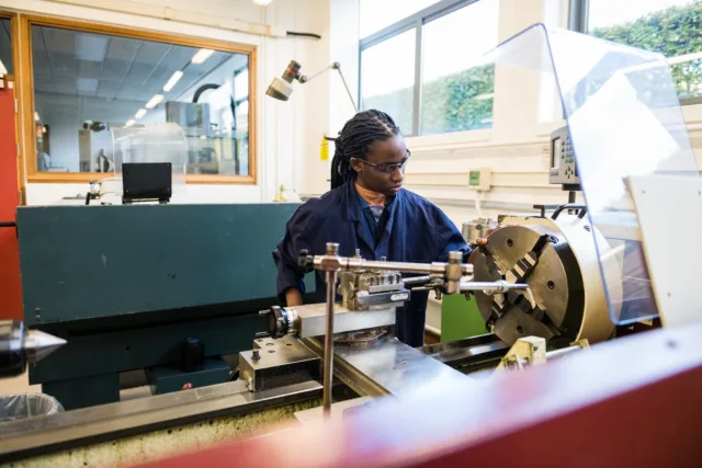 Female engineering student in navy overalls working at her engineering station