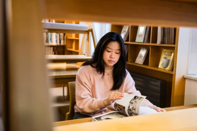 Female international student reading through book in the Wellpark Road library.