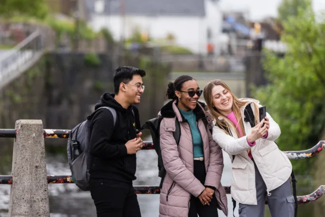 Three students, a male and two females, take a selfie together while exploring Galway City