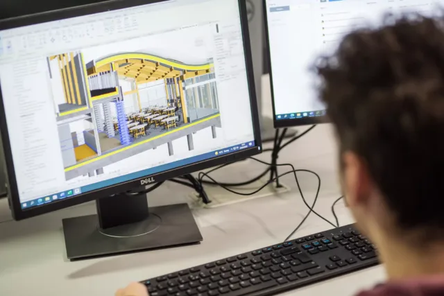 A student is working on a computer looking at technical plans for a building