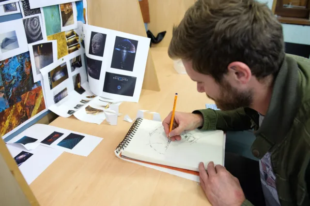 Male student sketching at a desk