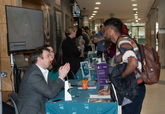 Postgraduate Information Day attendee speaking to lecturers at stands