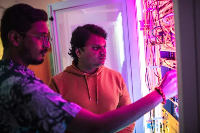 Students look at data storage hardware, lit by multi-coloured LED lights