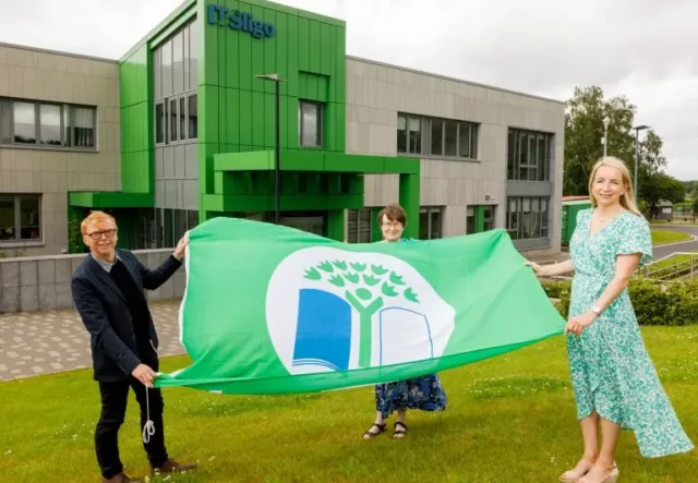 Green Campus flag held by 3 ATU staff