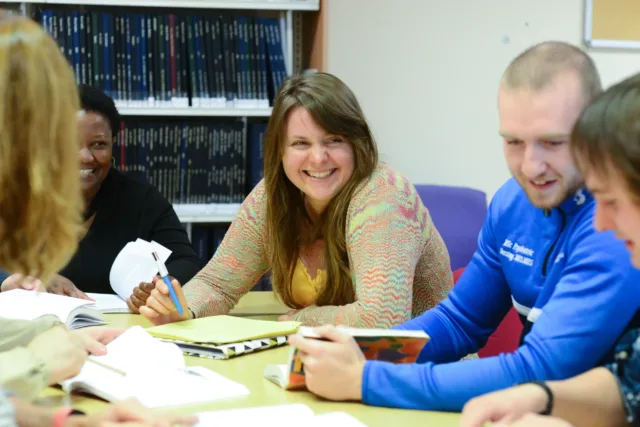 A group of students are sitting around a table working together