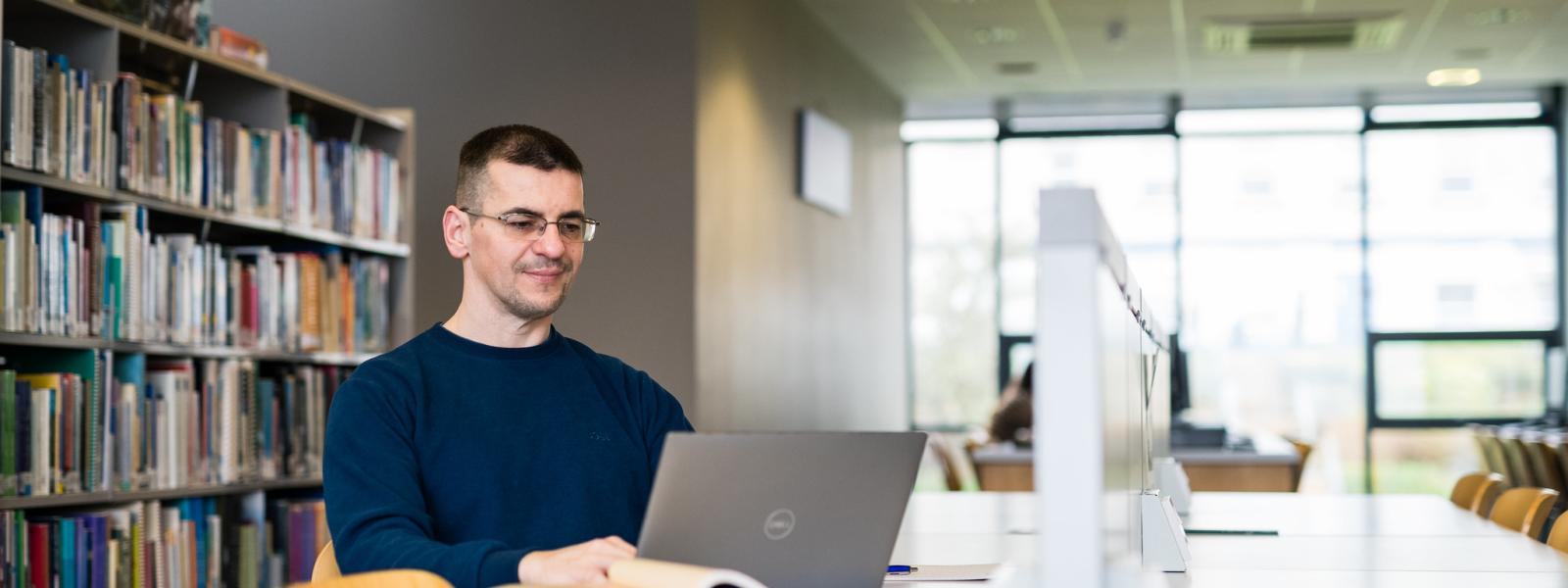 Student sitting at a desk with laptop and books